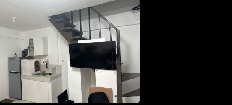 A small apartment with a kitchen, a wall-mounted TV and stairs